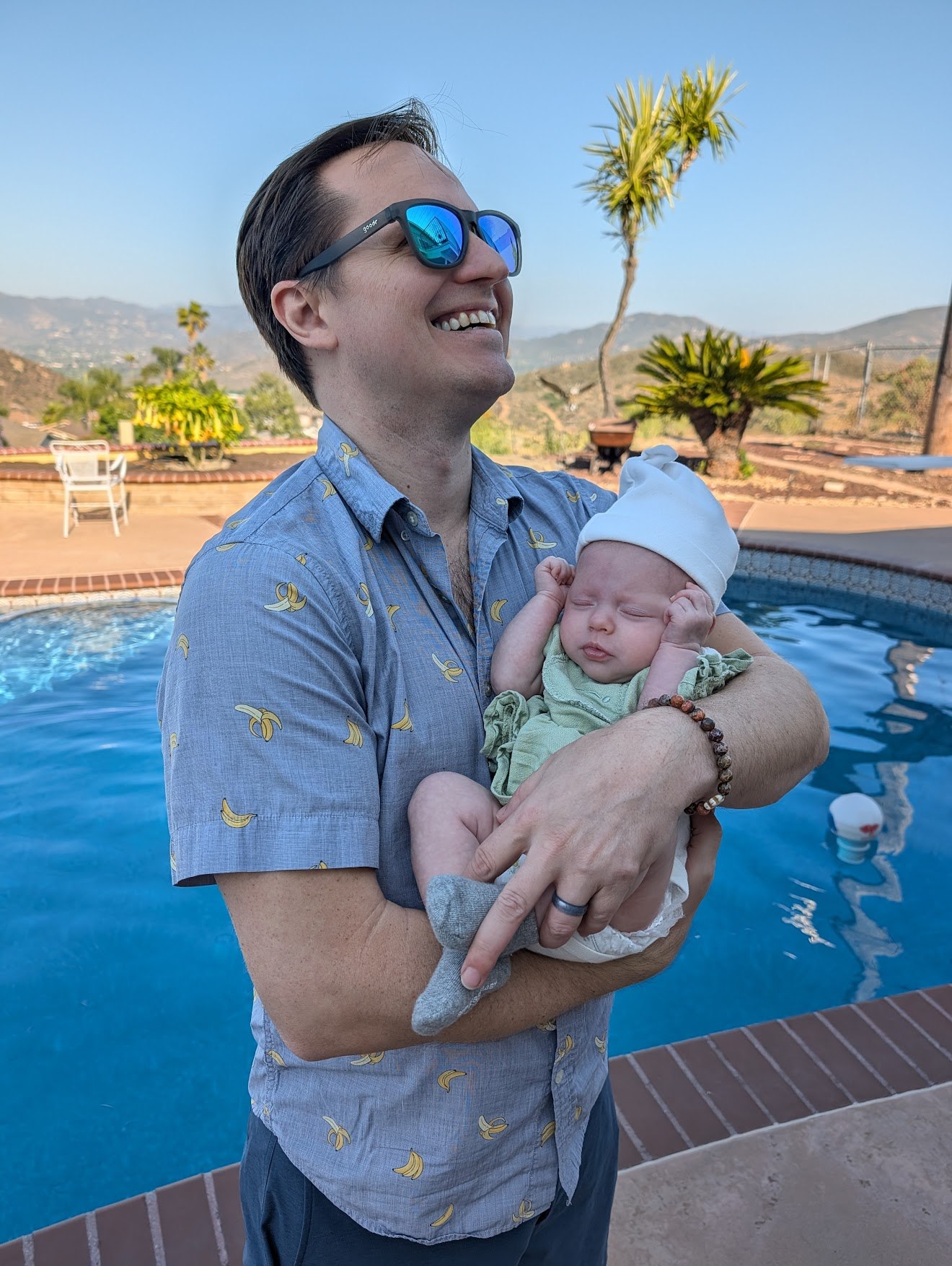 Don holding baby Riley by the pool — San Diego golden hour